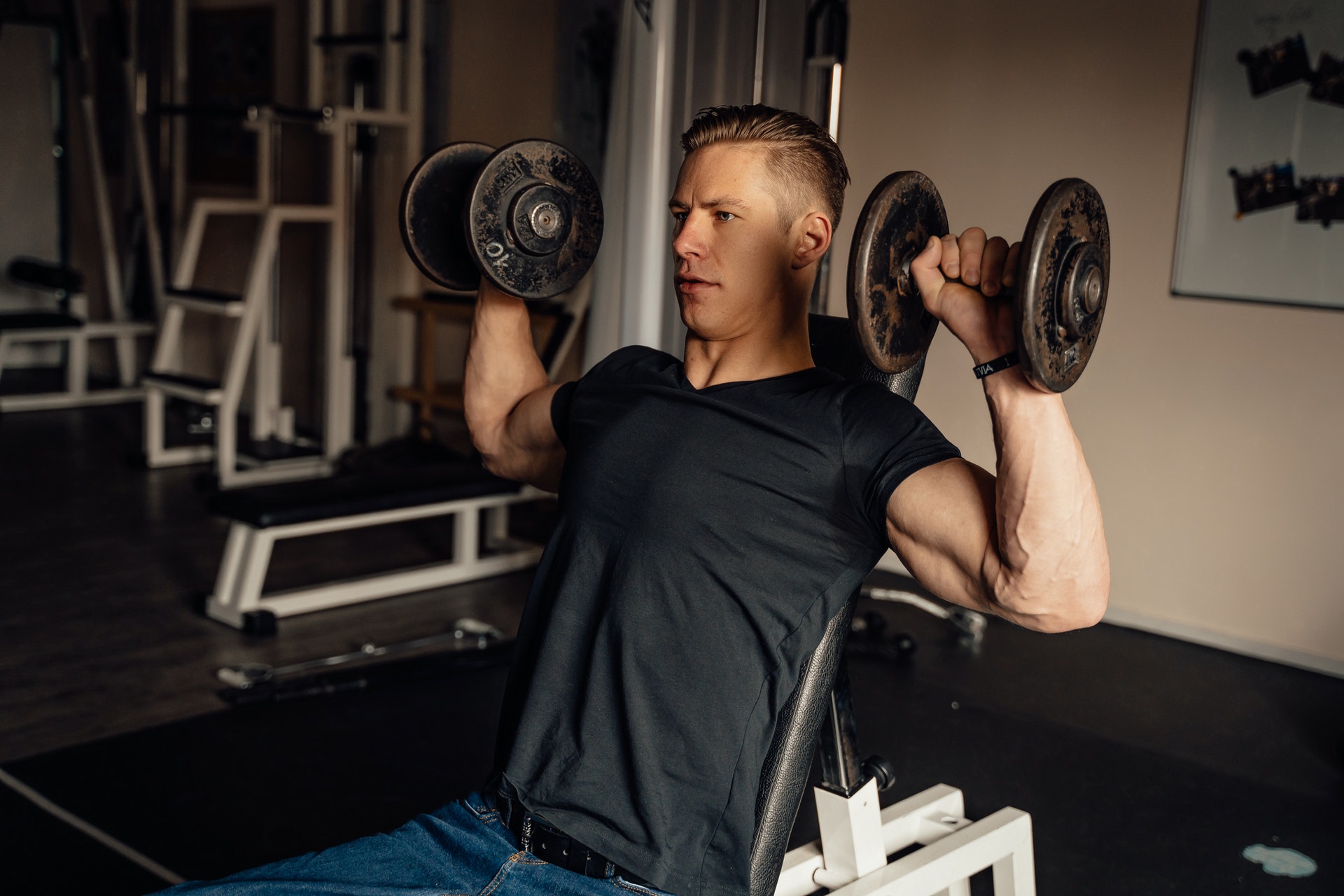 Man weight training by doing the shoulder press exercise using dumbbells 