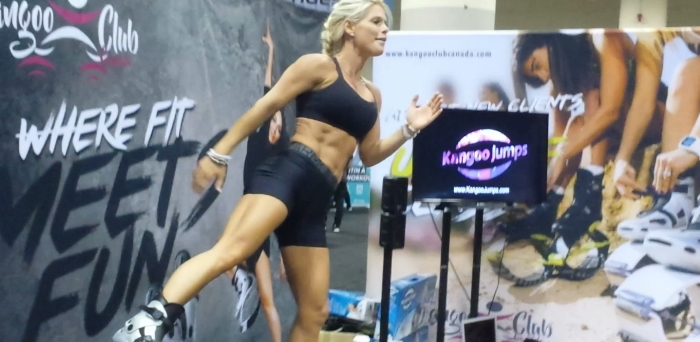 Blonde instructor giving a kangoo jumping exercise, group exercise class