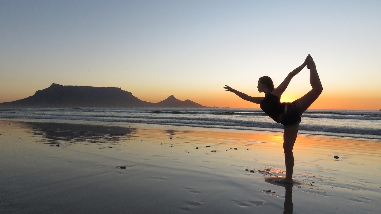 Woman doing a yoga pose on the beach during a sunset