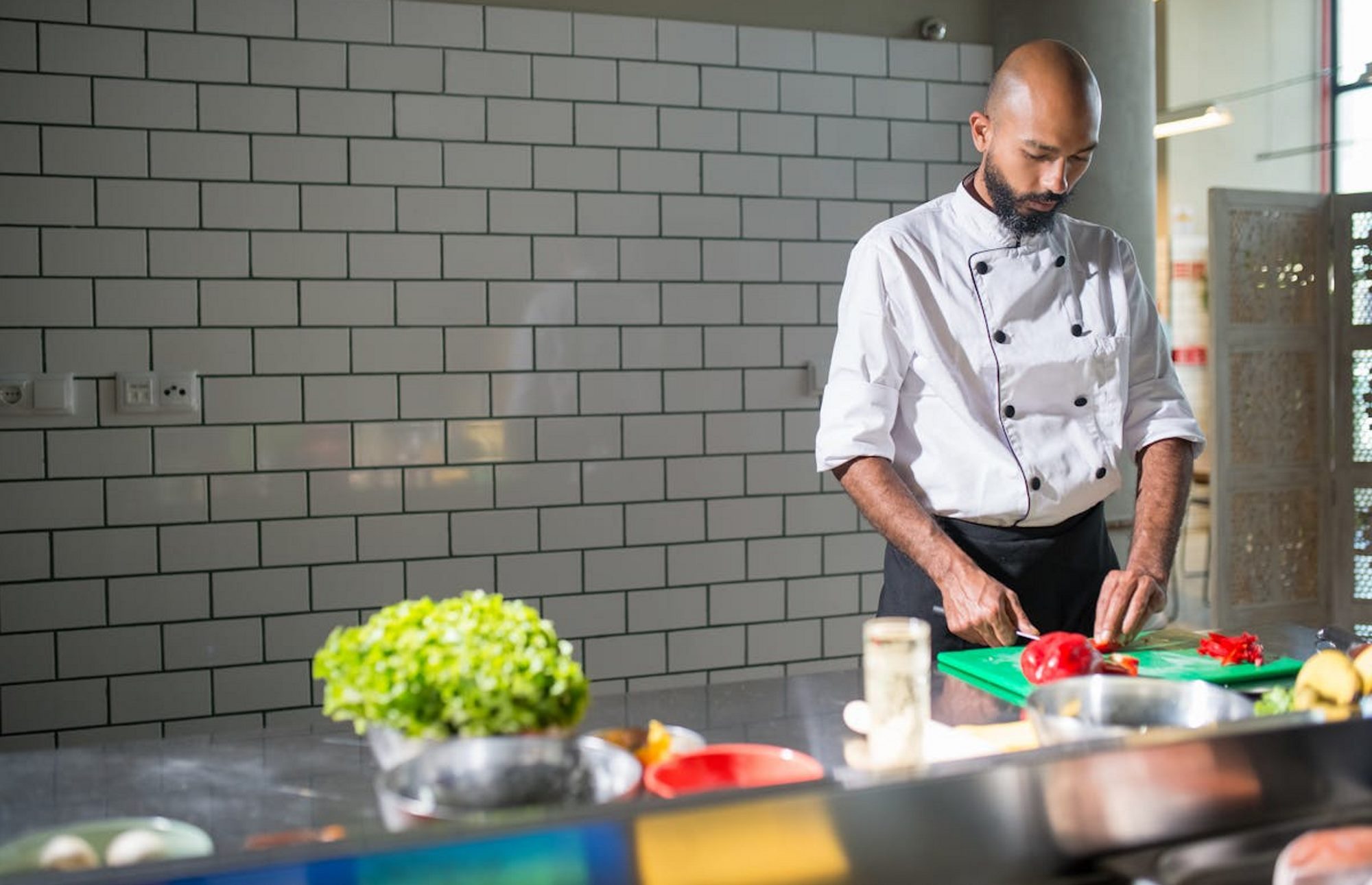 Chef in the kitchen preparing a healthy meal with vegetables.