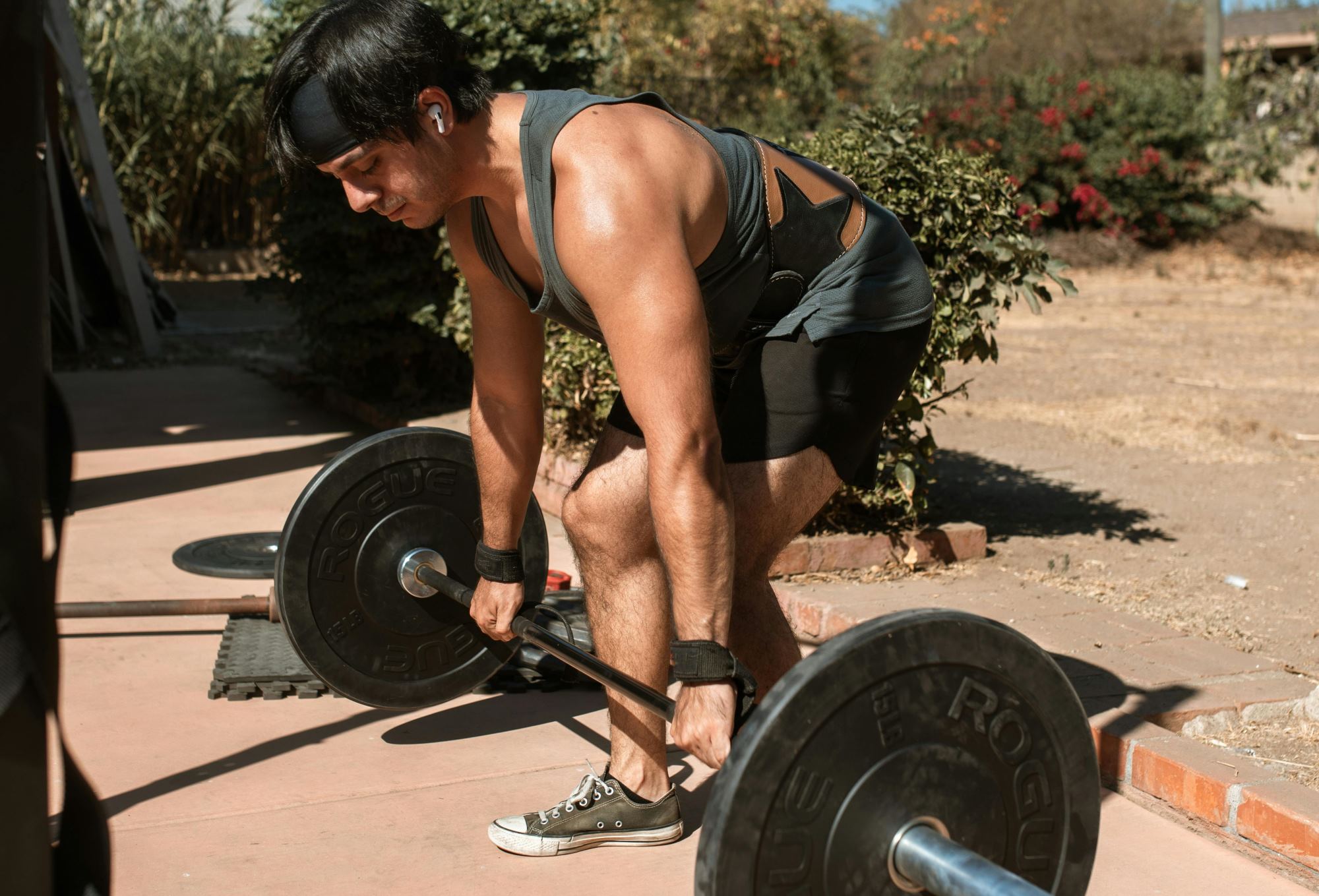 A man doing the deadlift exercise outside.