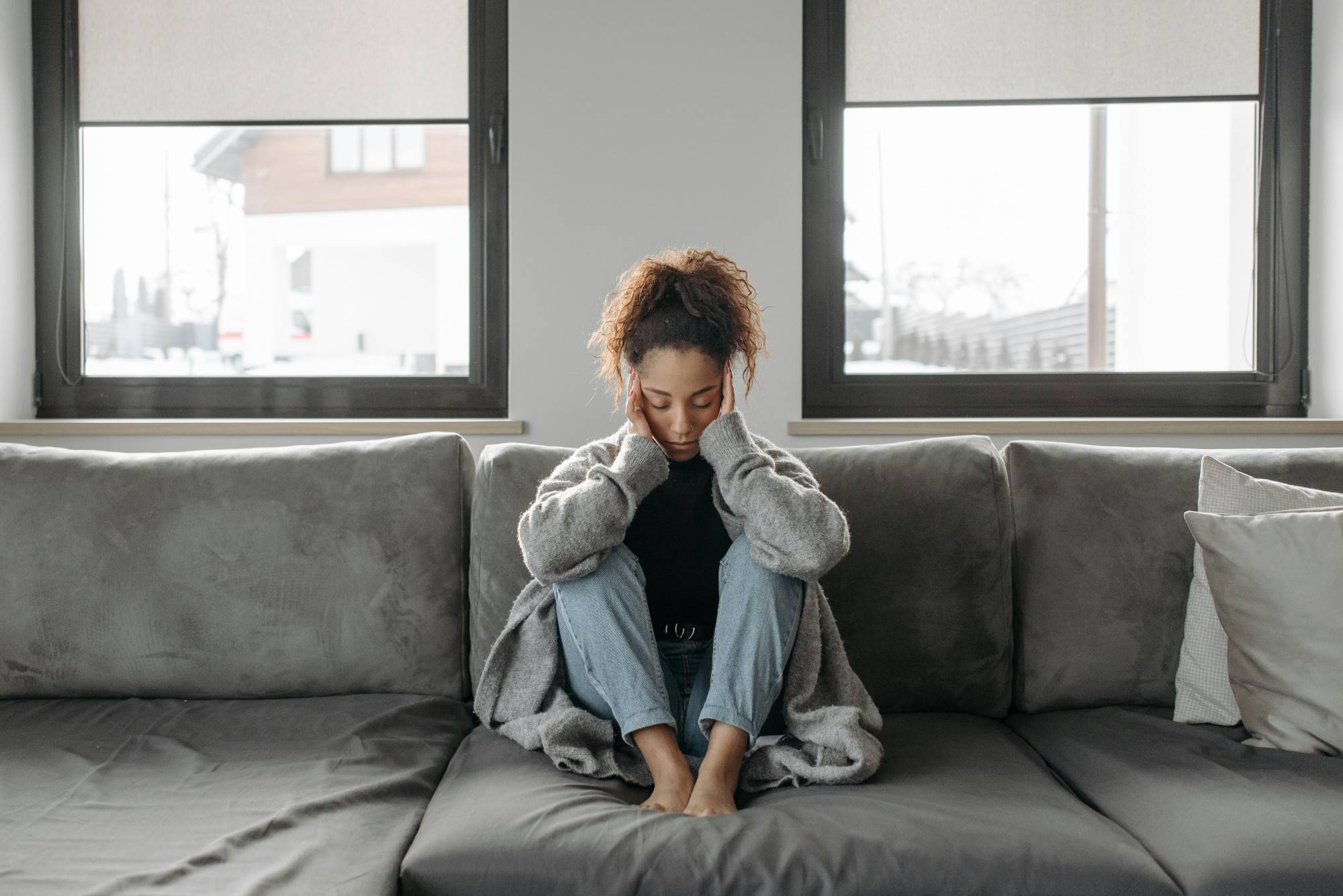 Woman sitting on sofa who has a migraine, headache.
