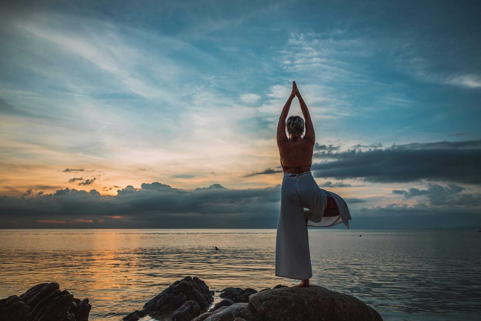 Woman doing a yoga pose during a sunset by the lake.